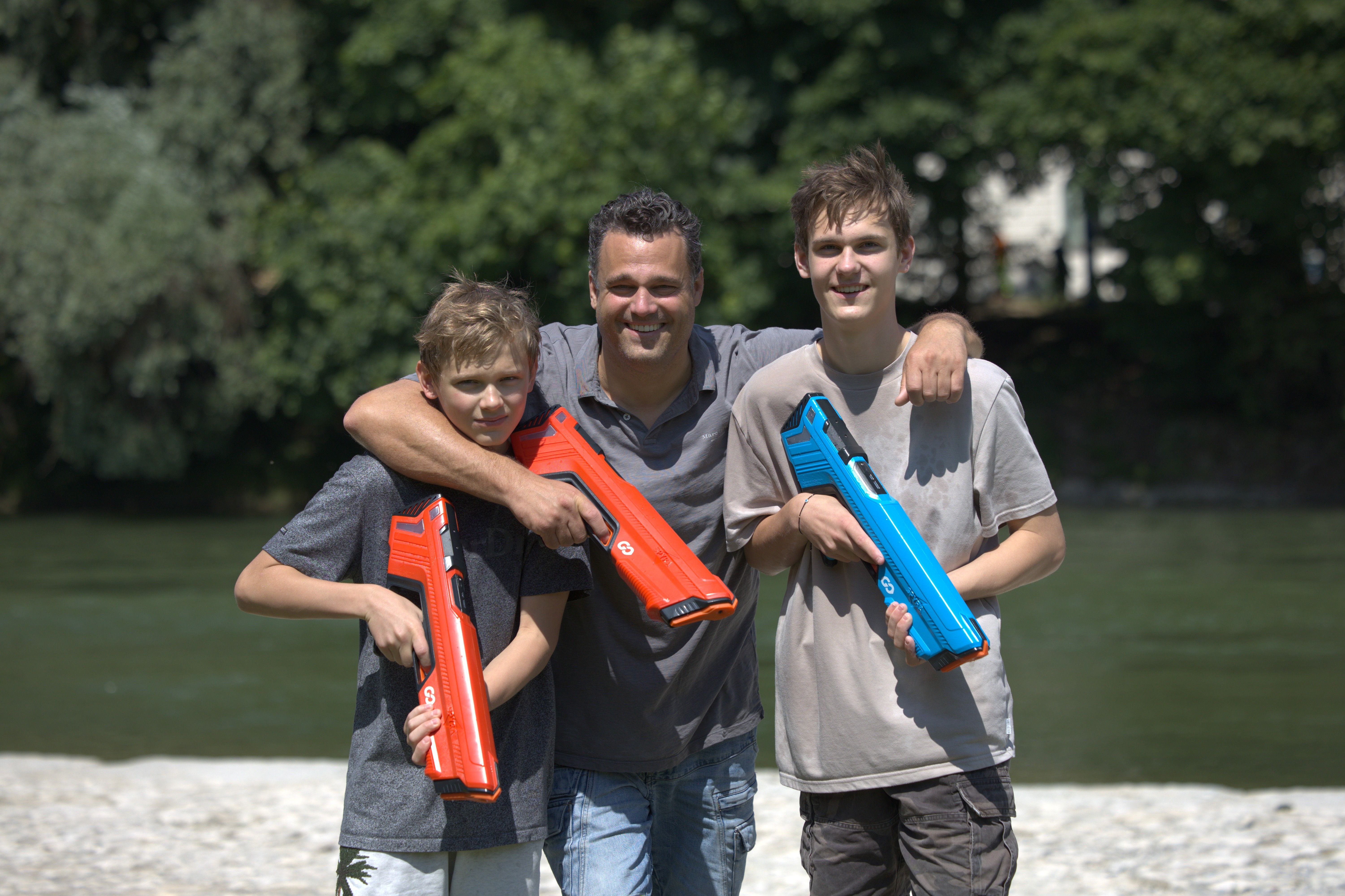 Vater und Söhne, die SpyraGO in der Hand halten, lachend 